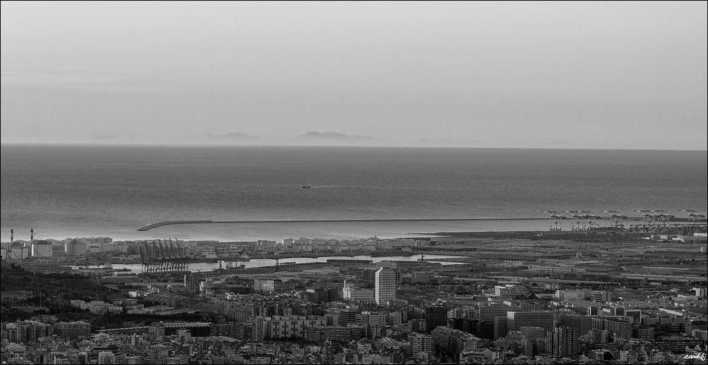 La silueta serrada de la Serra de Tramuntana flotando sobre el horizonte marino más allá del puerto de Barcelona, fotografiada al amanecer