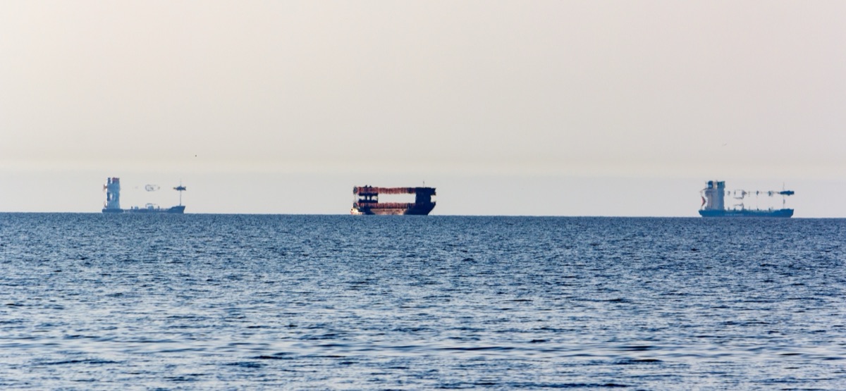 Tres cargueros en el golfo de Riga deformados por un espejismo superior, con los cascos estirados verticalmente y aparentemente flotando sobre el horizonte
