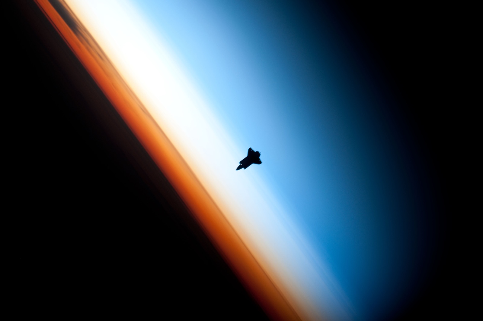 Silueta del transbordador espacial Endeavour contra el fino limbo atmosférico azul de la Tierra, fotografiada desde la EEI