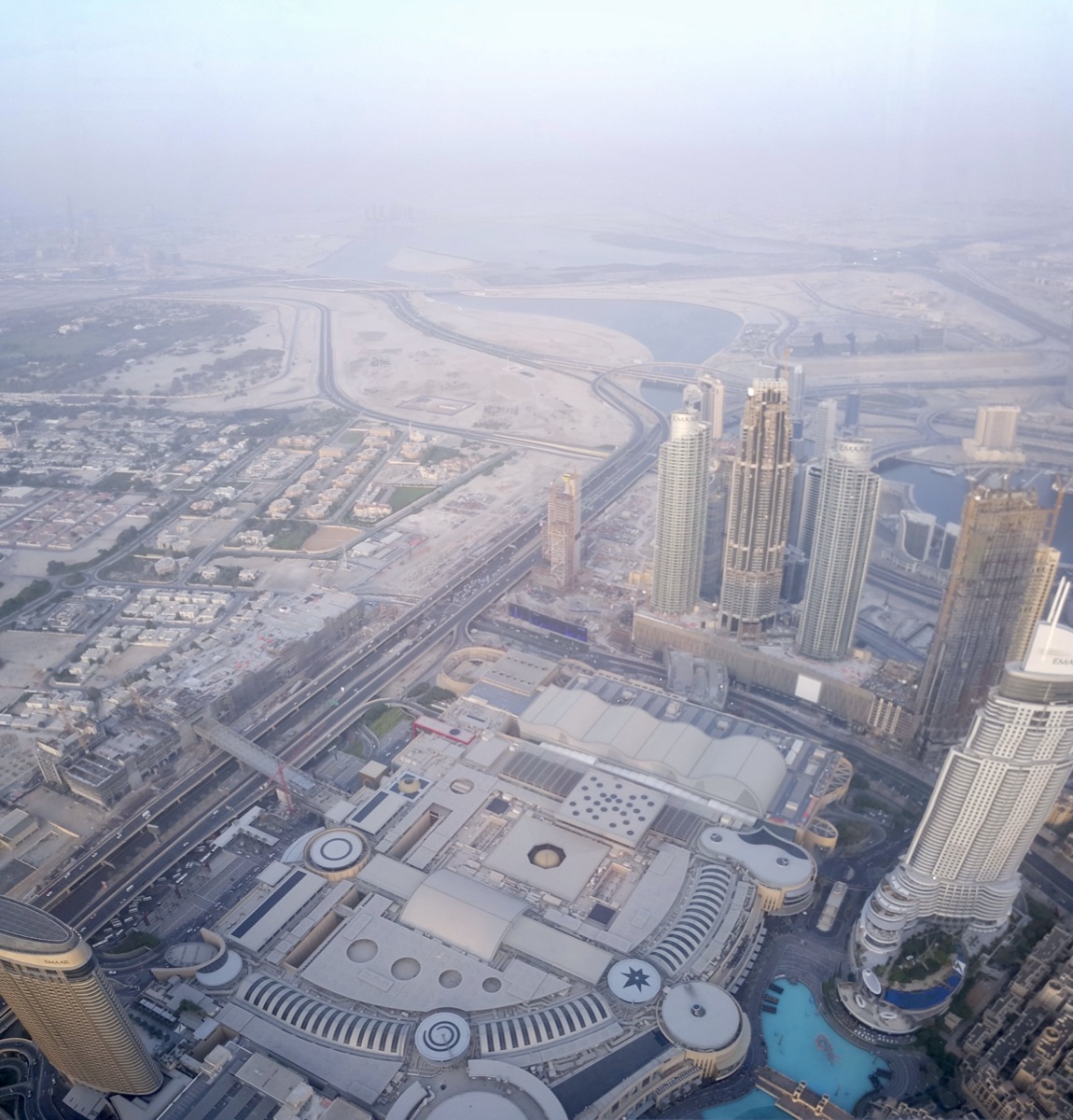 View from the Burj Khalifa's 148th-floor observation deck: downtown Dubai directly below, and the city dissolving into a wall of haze well before the horizon