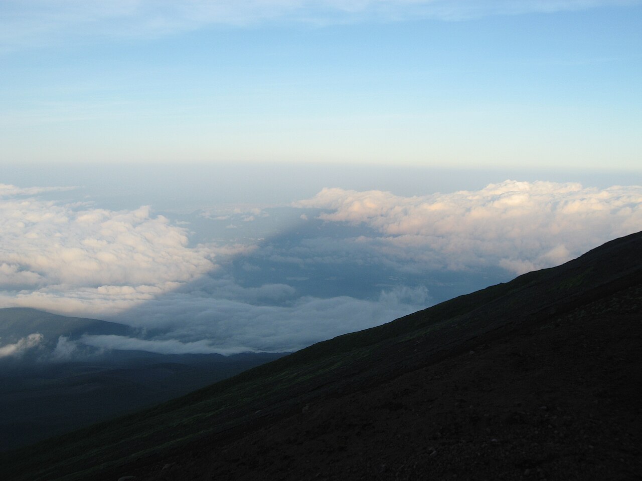La sombra del monte Fuji proyectada sobre un mar de nubes al amanecer, vista desde la ladera de la montaña