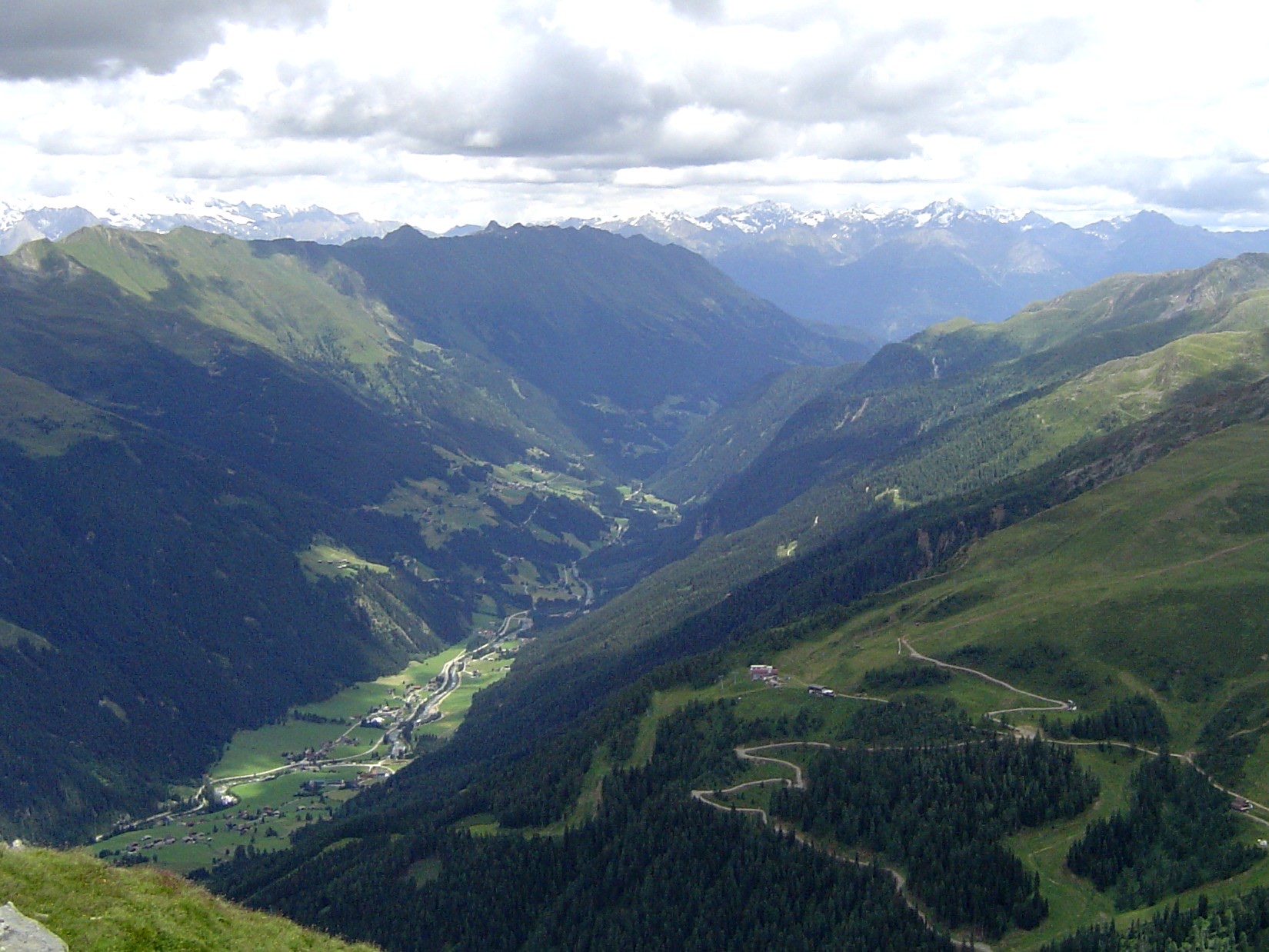 El Defereggental en el Tirol Oriental visto a lo largo de su eje desde arriba: una zanja profunda y estrecha en V con los pueblos alineados en su fondo verde y paredes altas a ambos lados