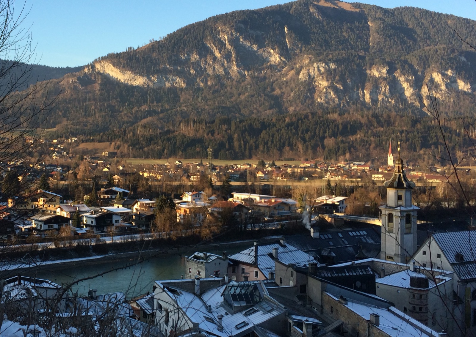 Rattenberg, en el Tirol, una tarde de diciembre: los tejados nevados del pueblo en primer plano quedan en sombra azulada mientras las casas de la otra orilla del Inn y la montaña que las domina siguen doradas por el sol bajo